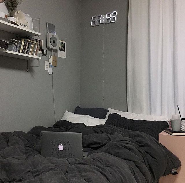 a laptop computer sitting on top of a bed in a bedroom next to a window