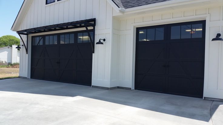 two black garage doors in front of a white house