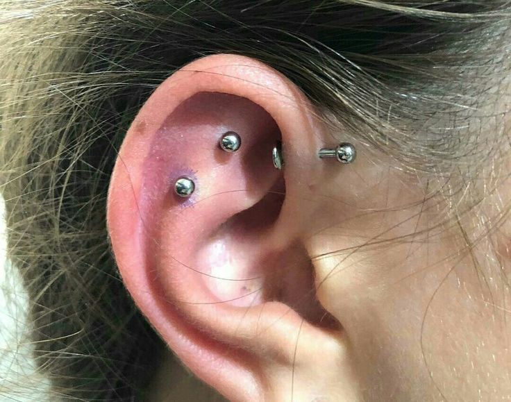 a woman's ear with three piercings on it