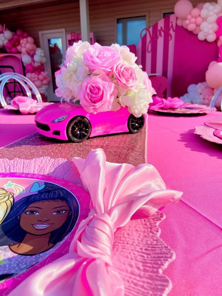 the table is set with pink plates, napkins and flower centerpieces on it