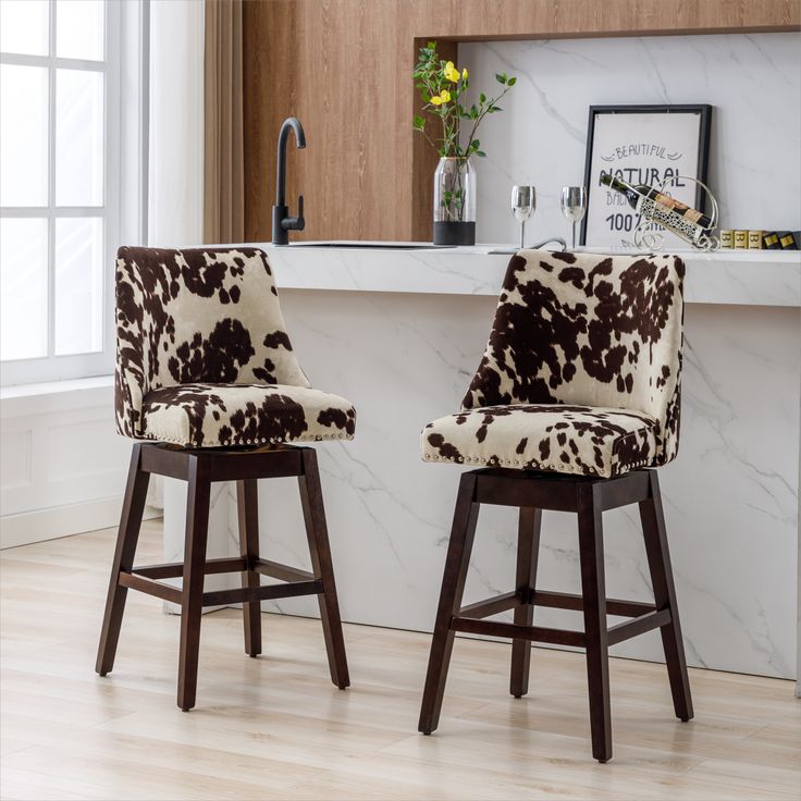 two brown and white cow print chairs in front of a counter with flowers on it