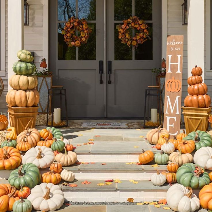 pumpkins and gourds on the front steps of a house with welcome sign