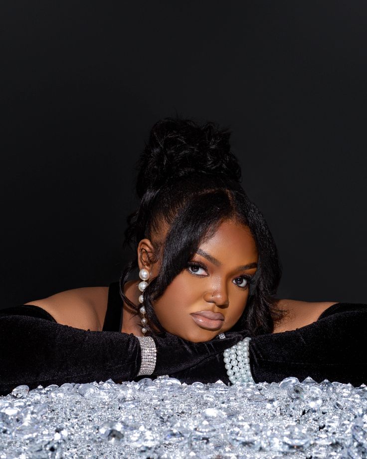 a woman laying on top of a table covered in silver glitters with her hands behind her head