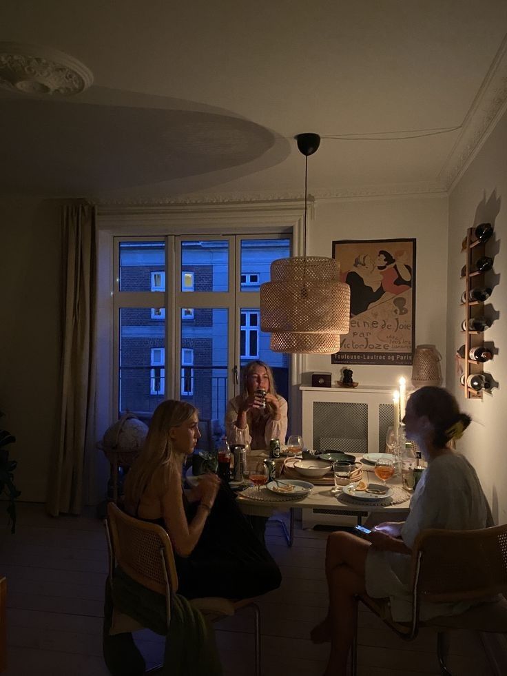 two women sitting at a table with food and drinks in front of a large window