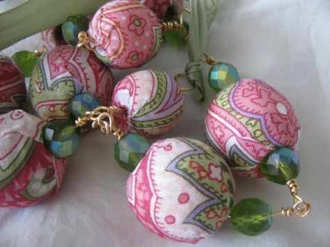 several pink and green bead necklaces on a white tablecloth with a zipper