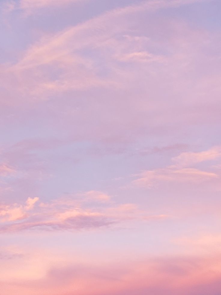 an airplane is flying in the sky with pink and blue clouds behind it at sunset