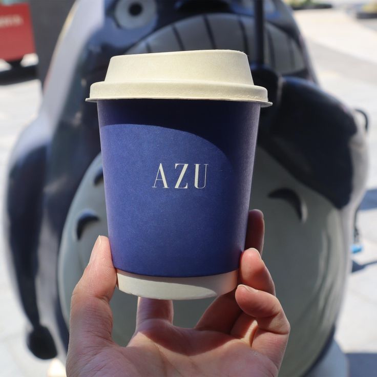 a person holding up a coffee cup with the word uza on it's side