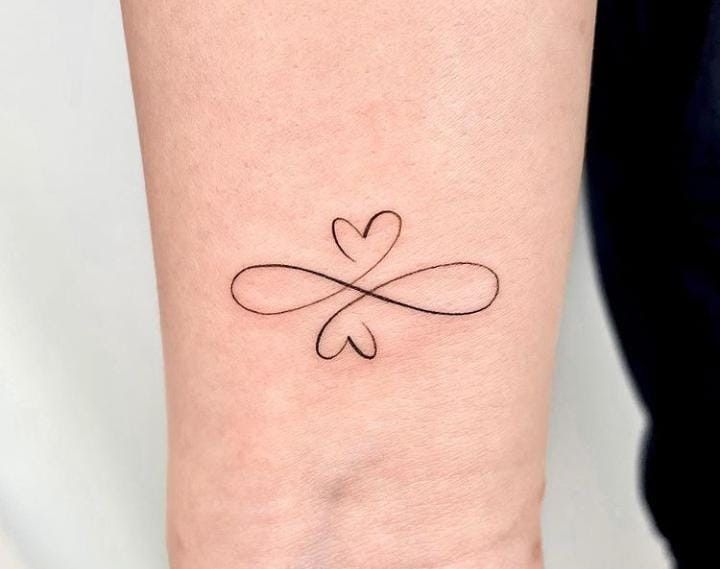 a woman's arm with a small heart tattoo on the left side of her wrist