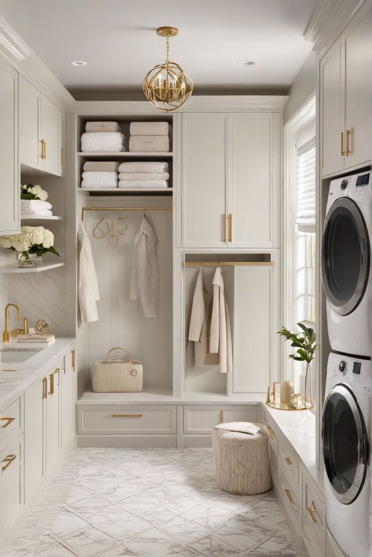 a washer and dryer in a white laundry room with gold hardware on the doors