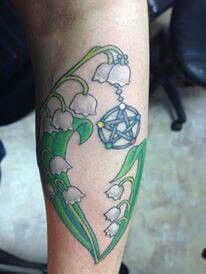 a tattoo on the leg of a person with lily of the valley flowers in it