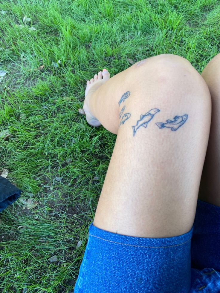 a person laying on the grass with their legs crossed and tattoos drawn on them,