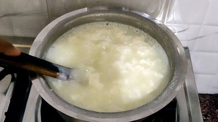 a person stirring food in a pot on the stove