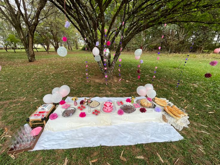 an outdoor picnic is set up in the grass with balloons and confetti on it