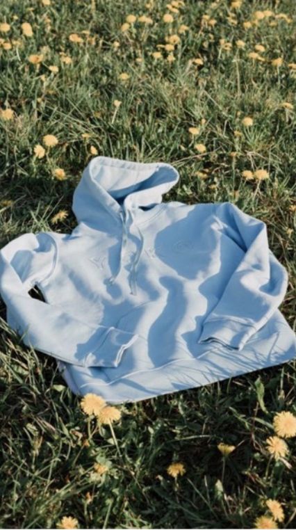 a blue shirt laying on top of a field of grass and yellow dandelions