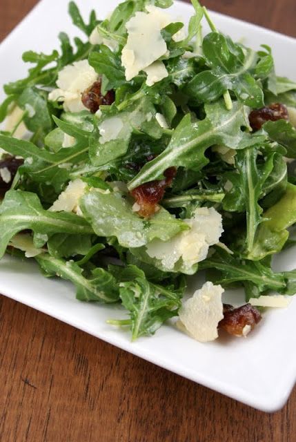 a white plate topped with salad on top of a wooden table