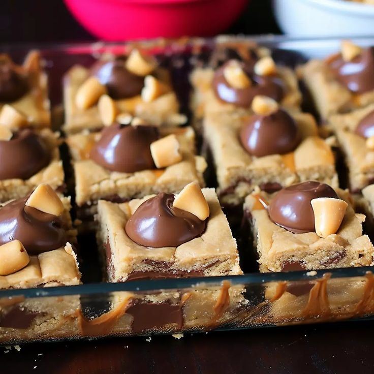 there are many pieces of dessert on the tray with peanut butter and chocolate toppings