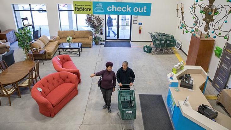 two women are walking down the stairs in a furniture store with shopping carts and couches