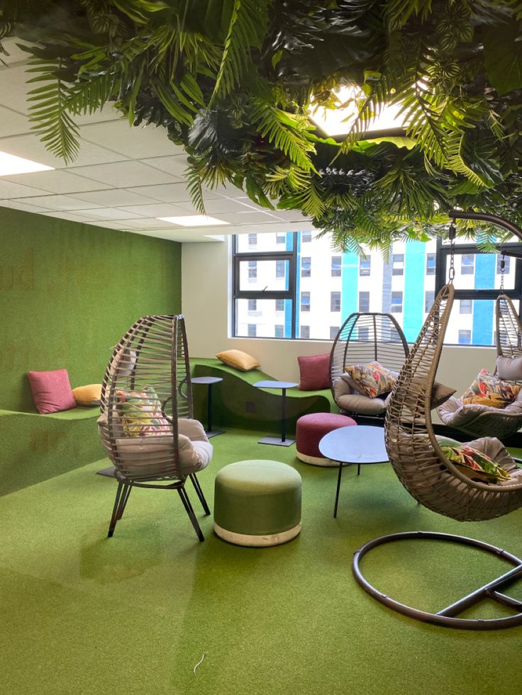 an office lounge area with hanging chairs, tables and other seating options for people to sit in