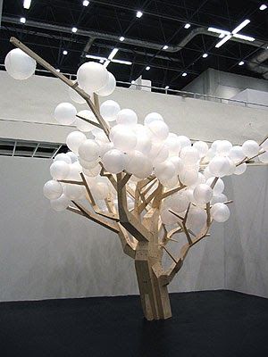 a tree with white balloons on it in a large room next to a wall and ceiling