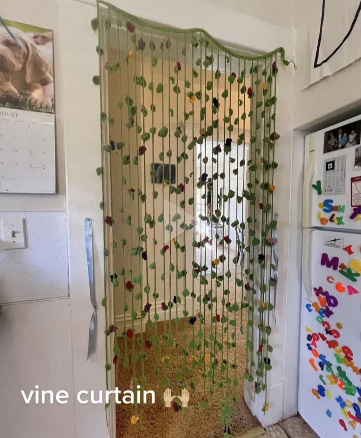 a kitchen with a door covered in vines and magnets next to a refrigerator freezer