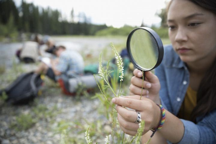 a girl looking through a magnifying glass at some people camping in the background