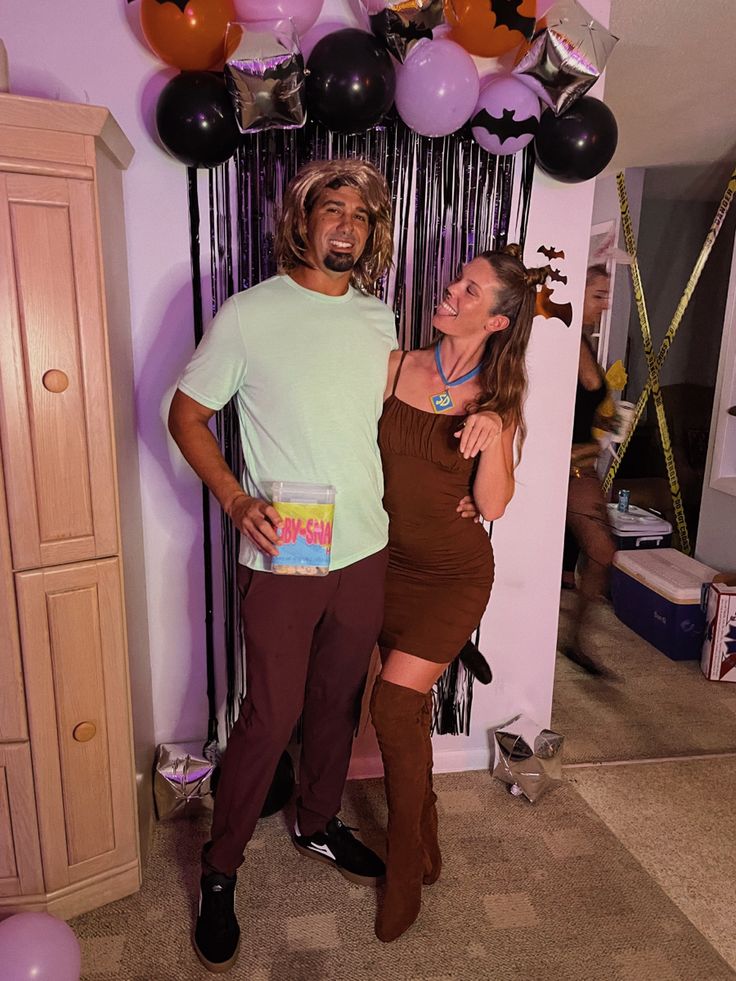 a man and woman standing next to each other in front of balloons on the wall