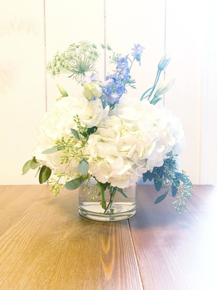 a glass vase filled with white and blue flowers