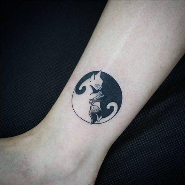 a cat and moon tattoo on the ankle is shown in black and grey ink,