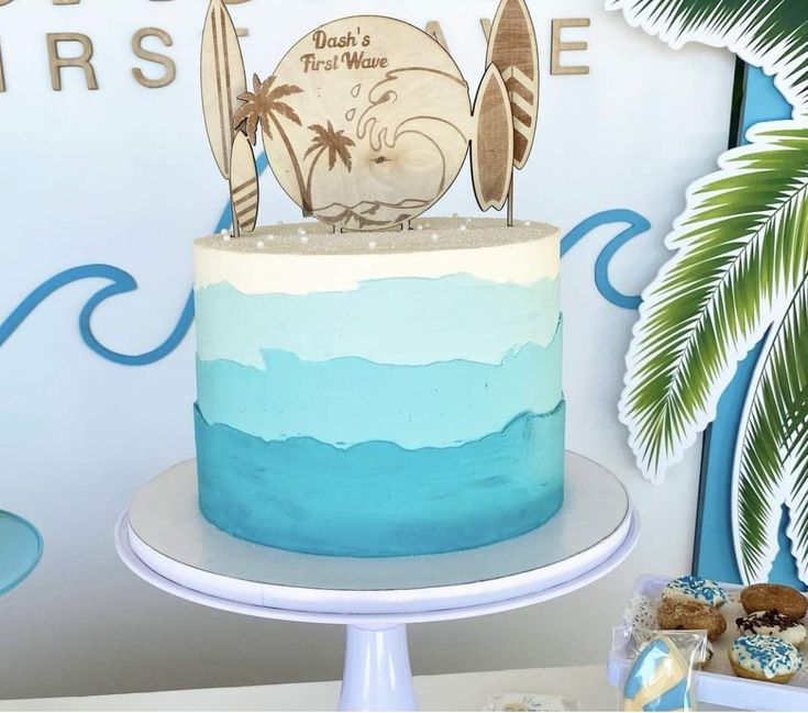 a blue and white cake sitting on top of a table next to a palm tree