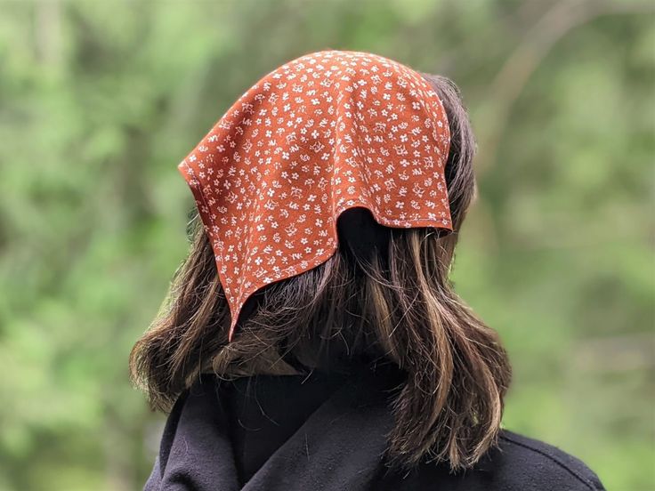 a woman with long hair wearing a bandana on her head and looking off into the distance