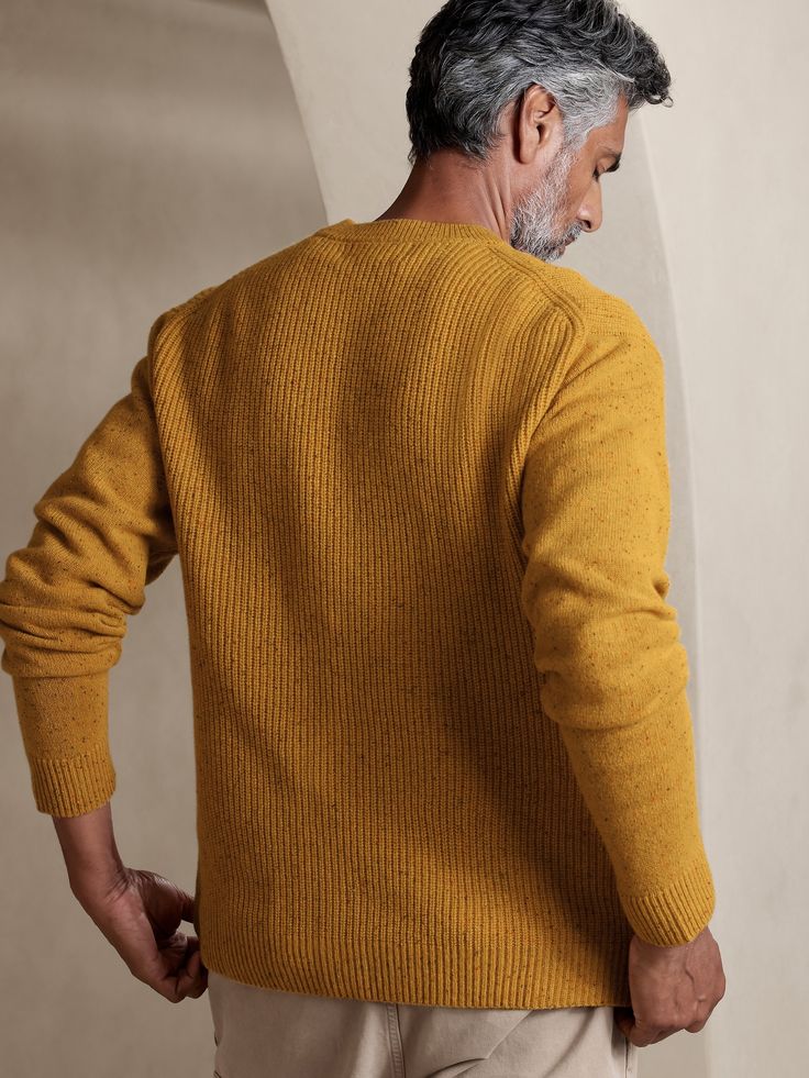 an older man wearing a mustard colored sweater and khaki pants with his back turned to the camera