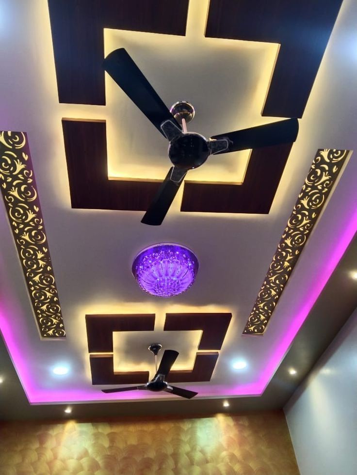 a ceiling with lights and a fan in the middle is lit up by purple lighting