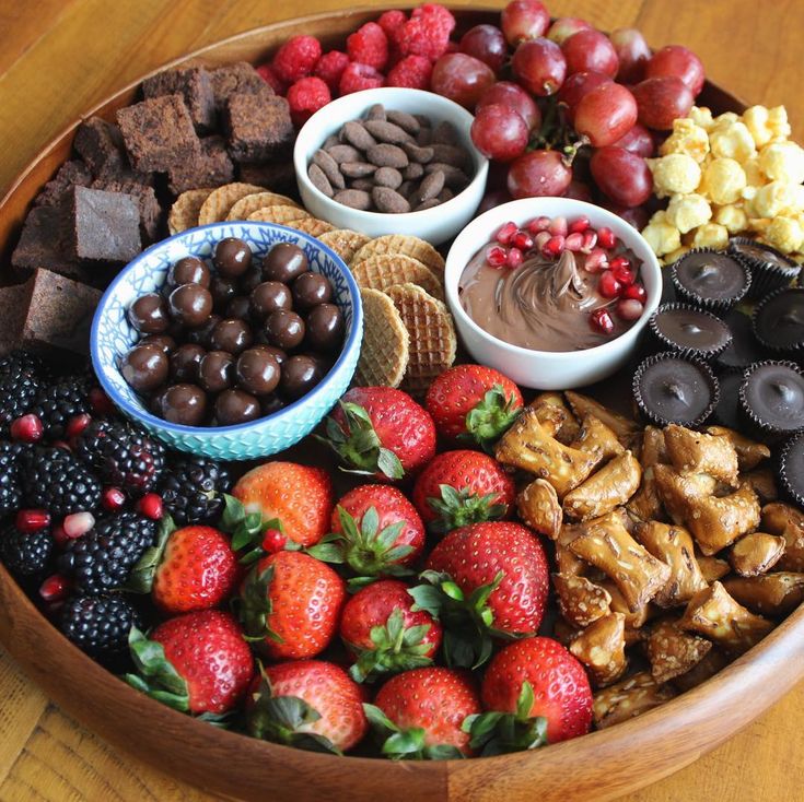 a wooden platter filled with chocolate, fruit and desserts on top of a table