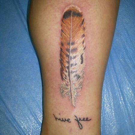 a tattoo on the leg of a woman with a feather and words written in cursive writing