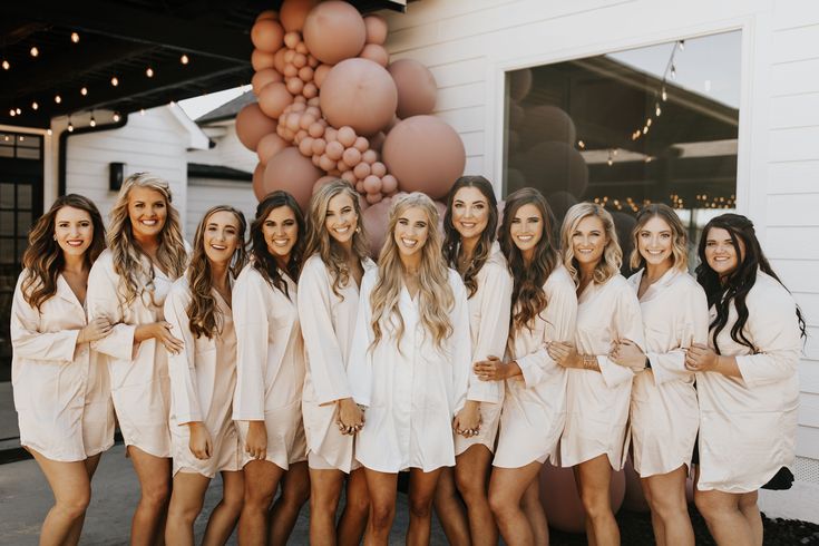 a group of women standing next to each other in front of a bunch of balloons