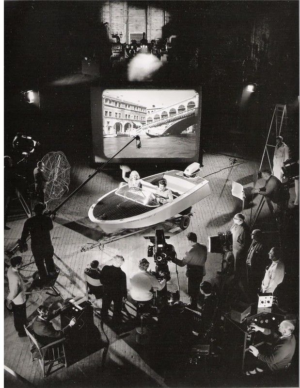 an old black and white photo of people around a boat on the television screen in a dark room