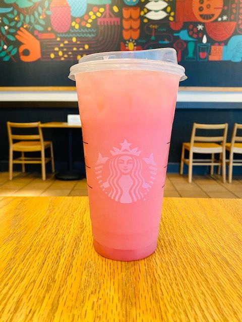 a pink starbucks cup sitting on top of a wooden table