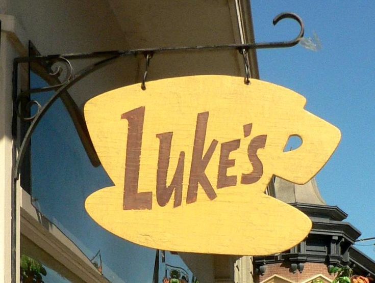 a wooden sign hanging from the side of a building