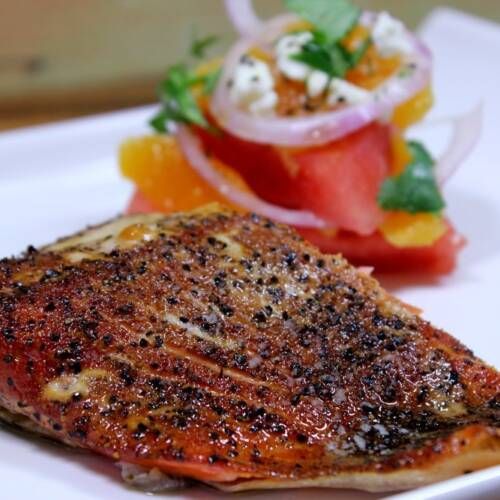 a white plate topped with fish next to a salad