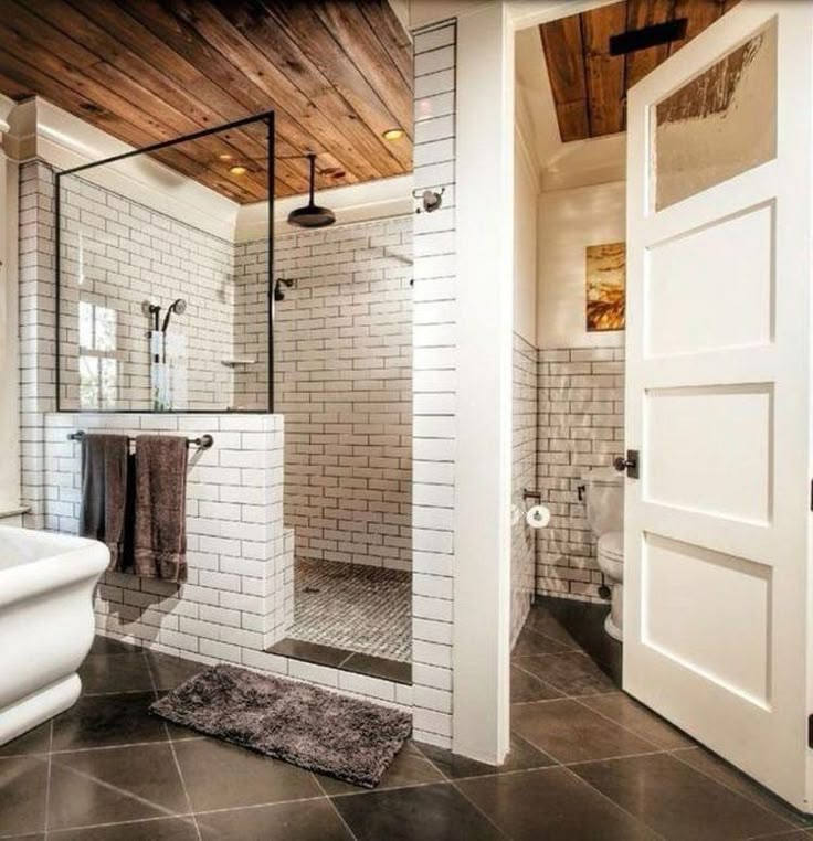 a bathroom with a walk in shower next to a white toilet and sink under a wooden ceiling