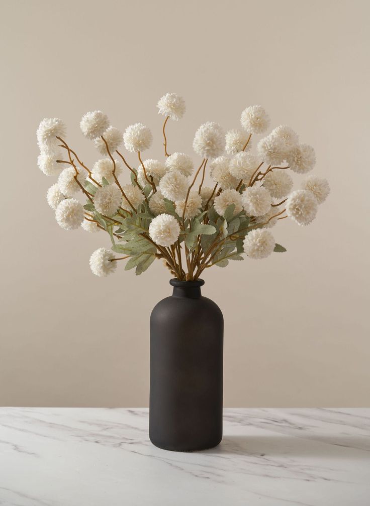 a black vase with white flowers in it