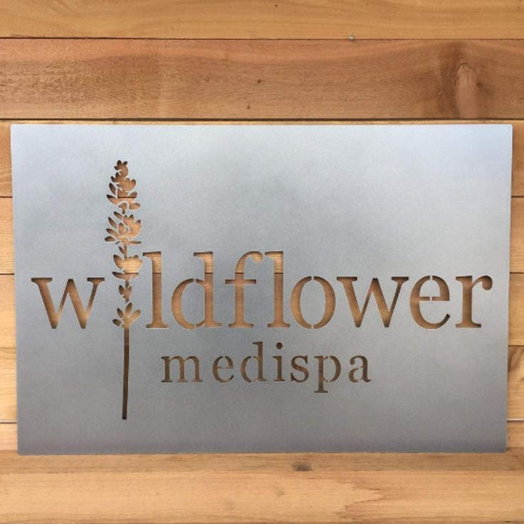 a metal sign that reads wildflower medispa on the side of a wooden wall