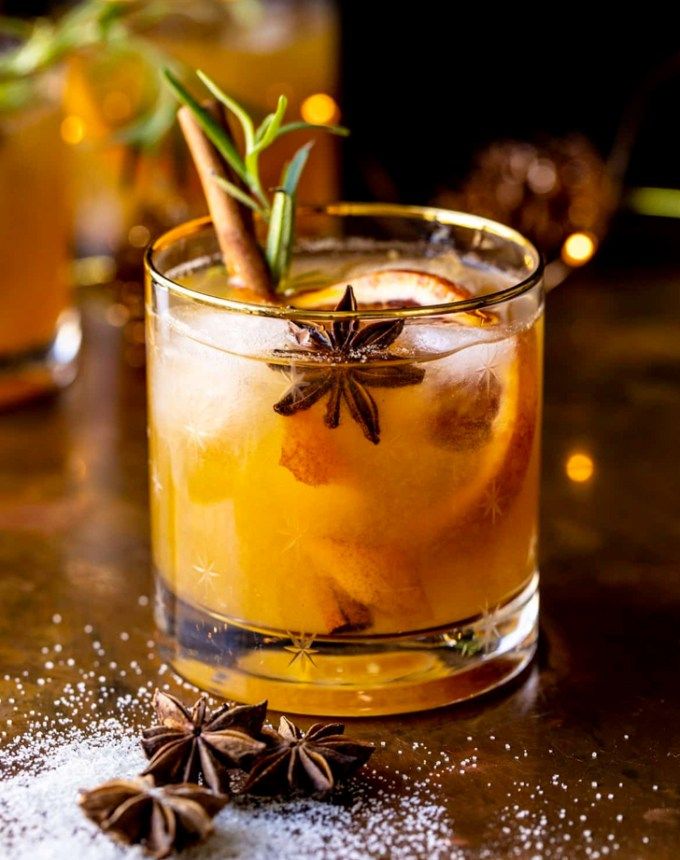 an old fashioned cocktail is garnished with cinnamon, star anise and spices