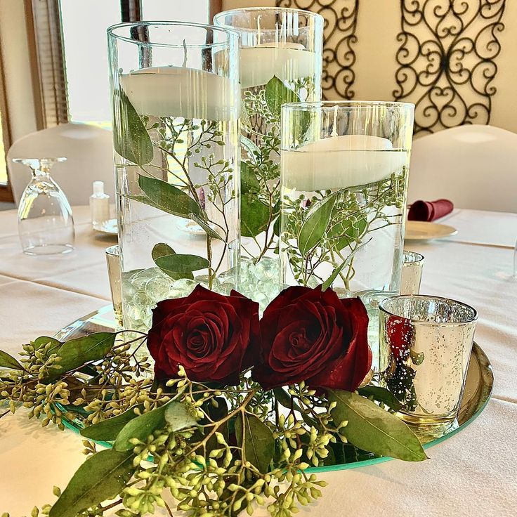 flowers and candles are arranged in glass vases on a table