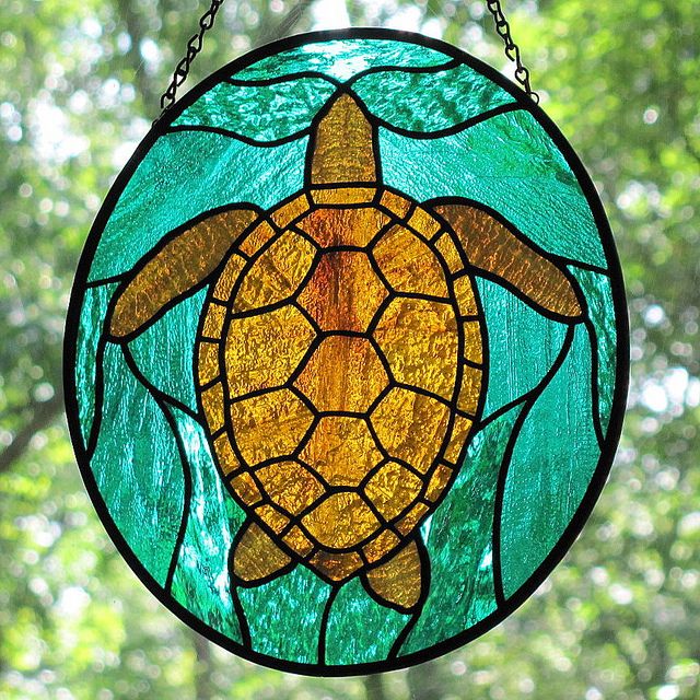 a stained glass window with a sea turtle on it's side and trees in the background