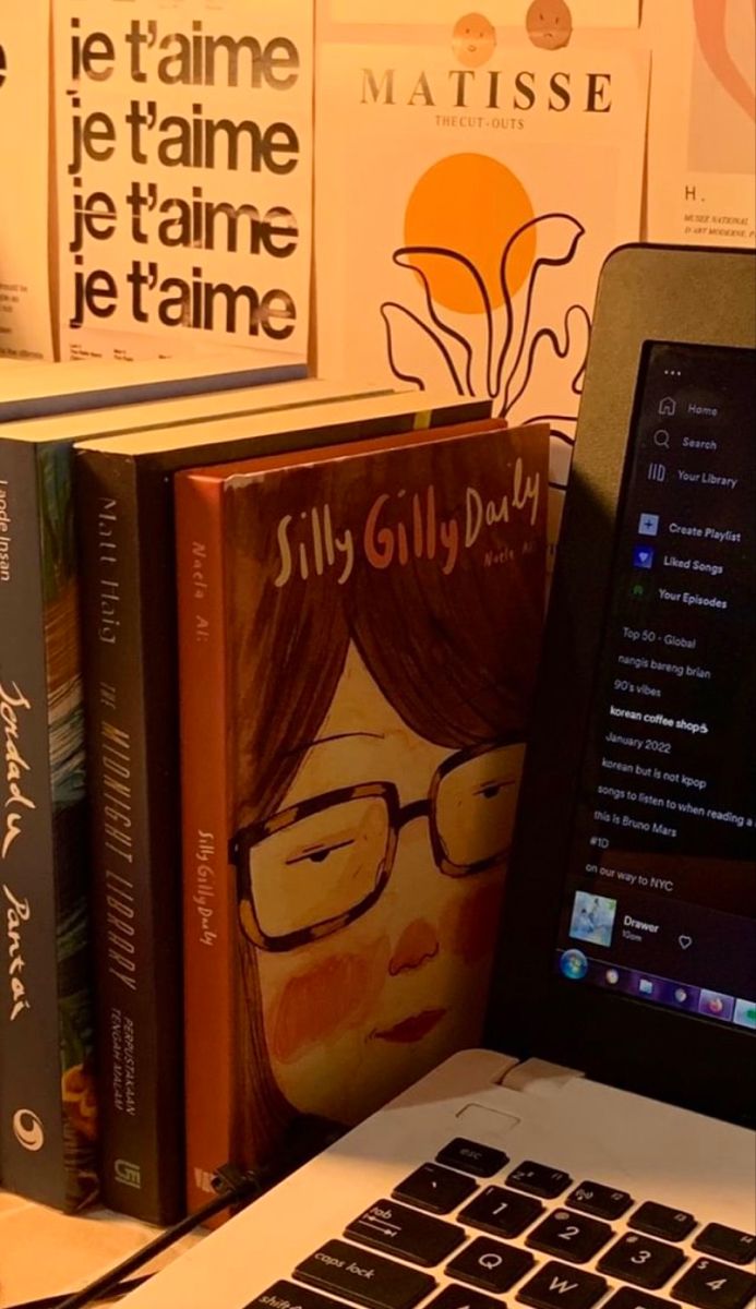 an open laptop computer sitting on top of a desk next to bookshelves and posters