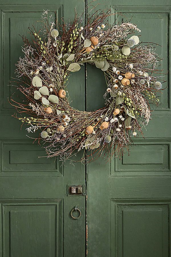 a green door with a wreath hanging on it's side and an egg in the middle