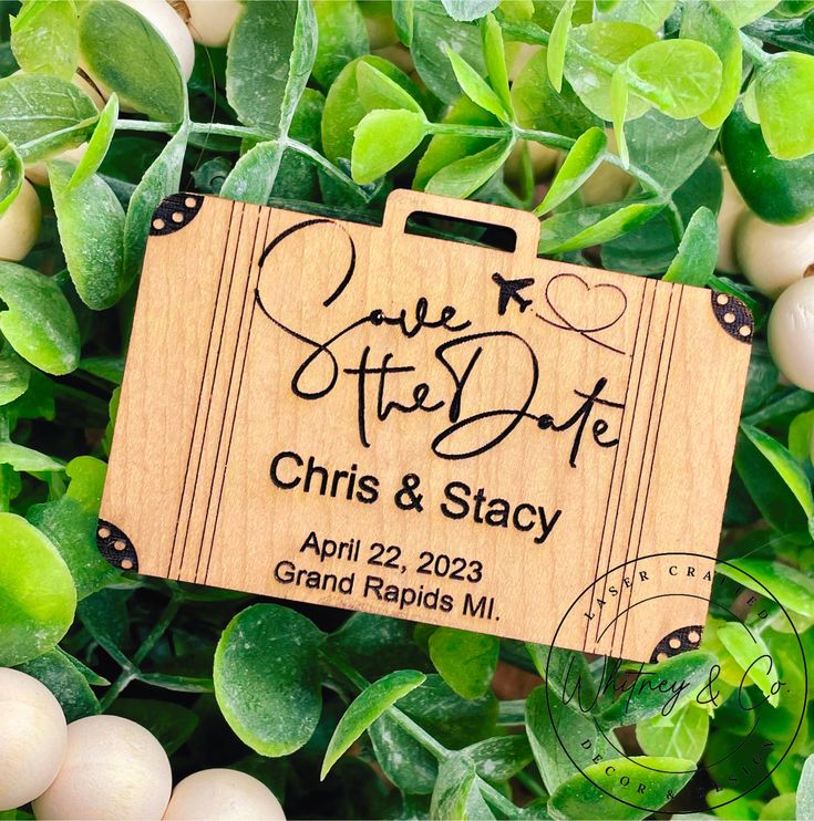 wooden save the date sign on top of green leaves