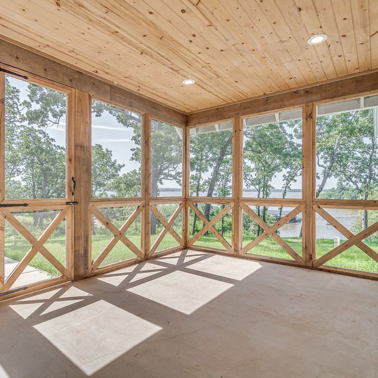 an empty room with large windows and wood paneling on the walls, overlooking a lake