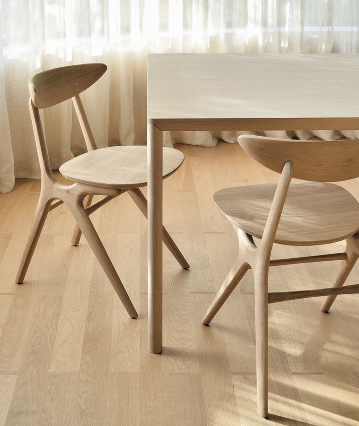 two wooden chairs sitting next to each other on top of a hard wood floored floor